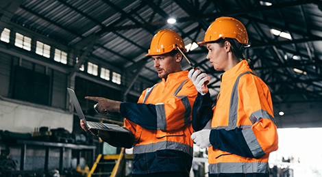 Two engineers wearing safety helmets and orange reflective jackets discuss industrial operate checking train maintenance at station, representing teamwork, safety and transportation and teamwork.